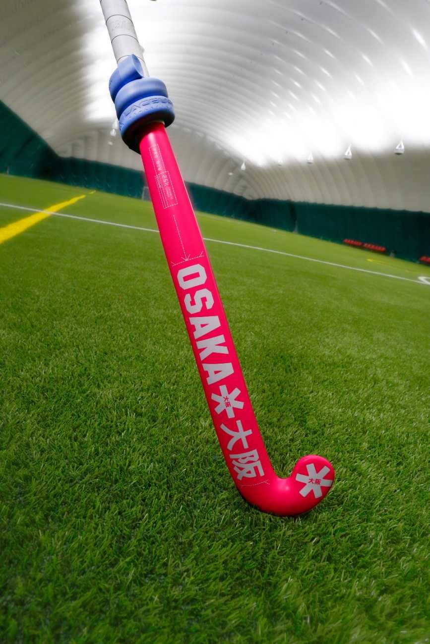a pink hockey stick on a green field