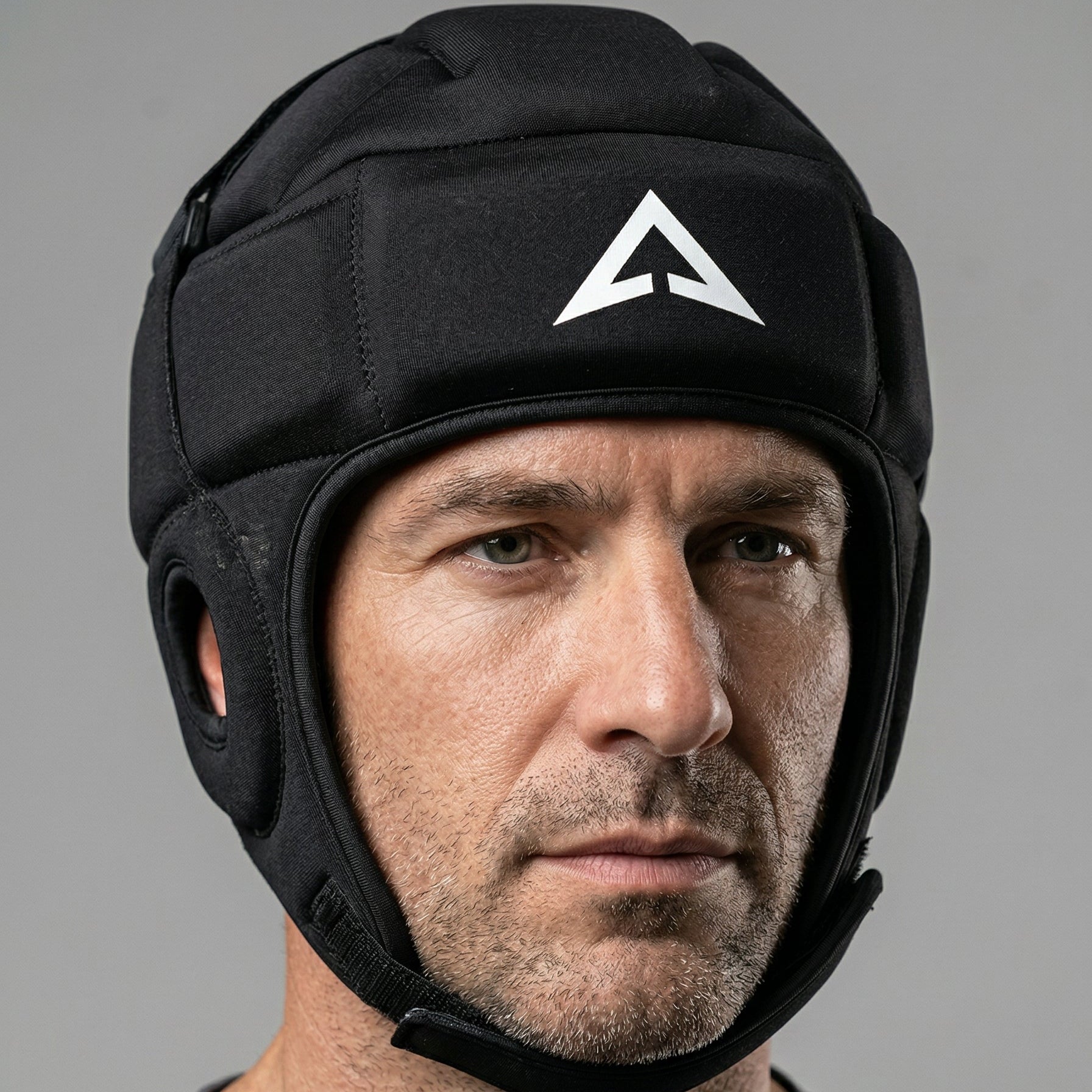 Man wearing a black helmet with a white logo on a gray background